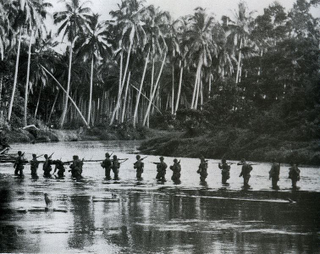 US Marines on patrol cross a river on the island of Guadalcanal